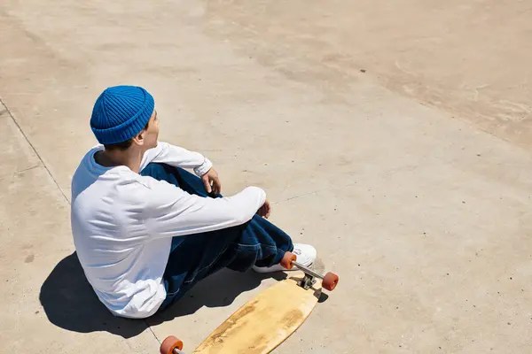 Relaxation under the sun at the park as a young man takes a break from skateboarding. — Stock Photo