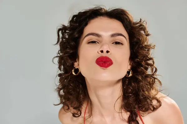 Young woman exudes confidence in stylish summer outfit, playfully blowing a kiss with red lips. — стокове фото