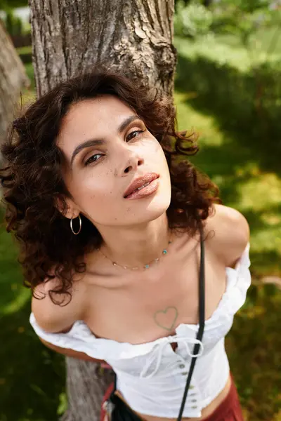 A young woman with curly hair enjoys summer while lounging outdoors by a tree. — Stock Photo