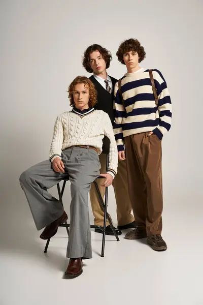 Trois jeunes amis posent en toute confiance dans des tenues branchées dans un décor studio minimaliste. — Stock Photo