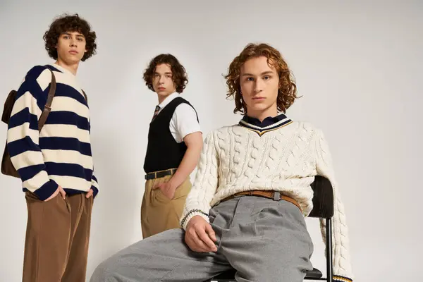 Three young men pose together, exuding confidence and style in a trendy studio backdrop. — стоковое фото