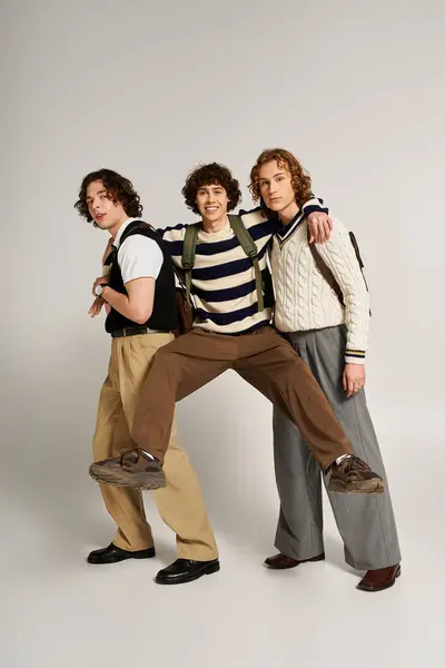 Three young men express camaraderie while showcasing trendy outfits in a playful indoor setting. — Stock Photo