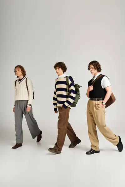 Three young men dressed in fashionable attire stroll together, showcasing their unique styles. — стоковое фото