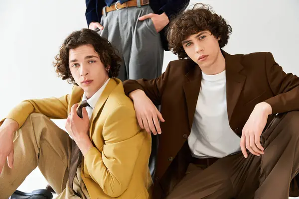 Jóvenes amigos en trajes de moda posan con confianza, mostrando sus estilos únicos y vínculo. - foto de stock