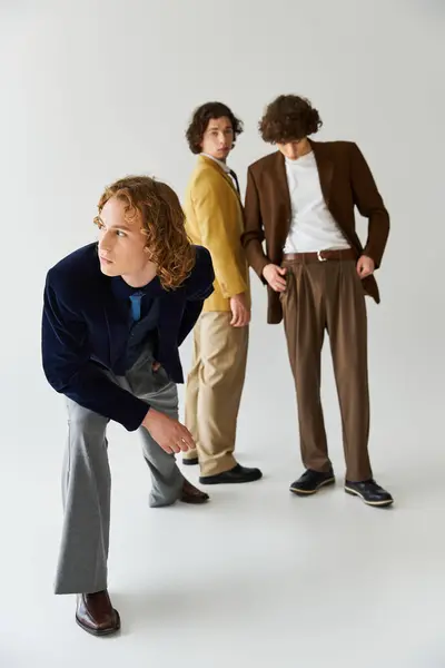 Three young men pose creatively in fashionable attire, highlighting their distinct styles. — Stock Photo