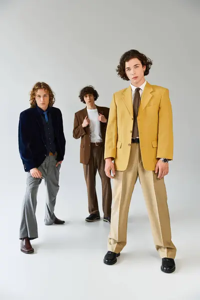 Three young men display their fashionable outfits in a contemporary studio, radiating confidence. — Stock Photo