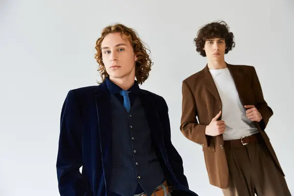 Two young men strike confident poses, showcasing their unique fashion in a bright studio. — Stock Photo