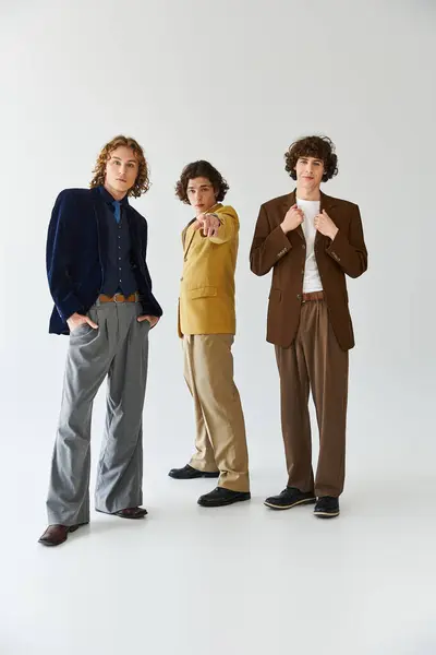 Three young men showcase their unique fashion choices while striking dynamic poses together. — Stock Photo