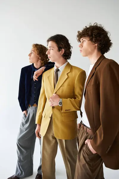 Three fashionable young men pose confidently together, highlighting their unique styles. — Stock Photo
