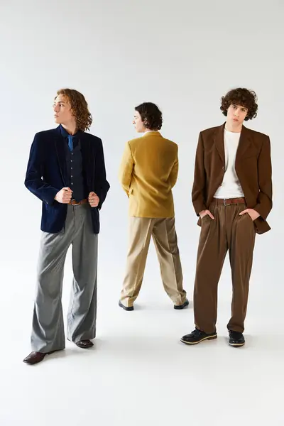 Three young men exude confidence and style while posing together in a creative environment. — Stock Photo