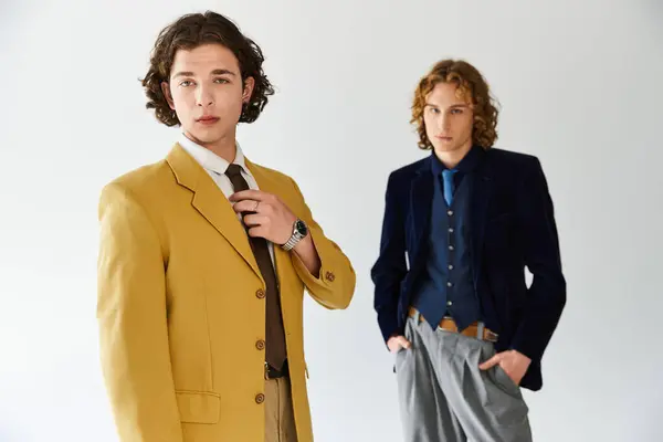 Deux jeunes hommes posent avec confiance, exprimant leur sens unique de la mode dans une atmosphère animée. — Stock Photo