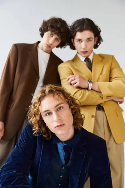 Three stylish young men confidently pose together in a minimalist studio. — Stock Photo