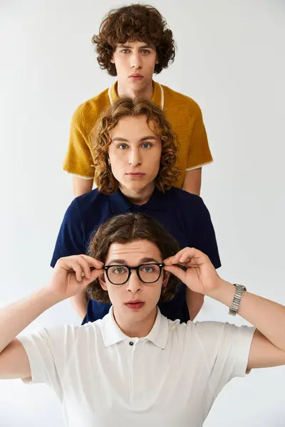 Three stylish young men pose confidently, showcasing their unique styles against a simple backdrop. — Stock Photo
