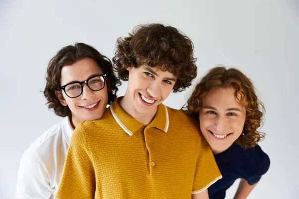 Tres jóvenes muestran sus elegantes trajes y sonrisas en un entorno luminoso y aireado. — Stock Photo