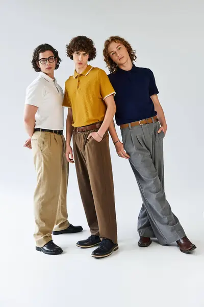 Trois jeunes hommes branchés posent ensemble, exprimant leurs styles uniques dans un cadre studio lumineux. — Stock Photo