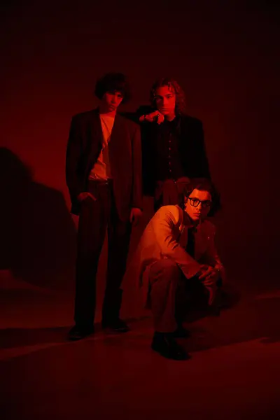 Three young men showcase their unique styles in a creatively lit, modern setting. — стоковое фото