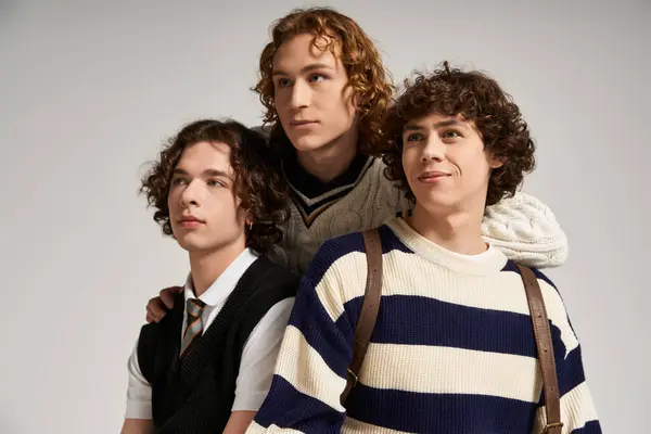 Three young men pose confidently in trendy outfits against a simple backdrop. — Stock Photo