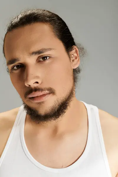 Young man with a beard showcases a confident expression in a minimalistic setting. — Stock Photo
