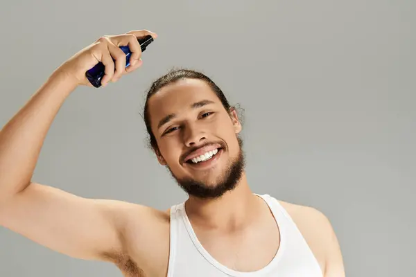 Young man with a beard smiles while applying hair product in a modern studio setting. — Stock Photo