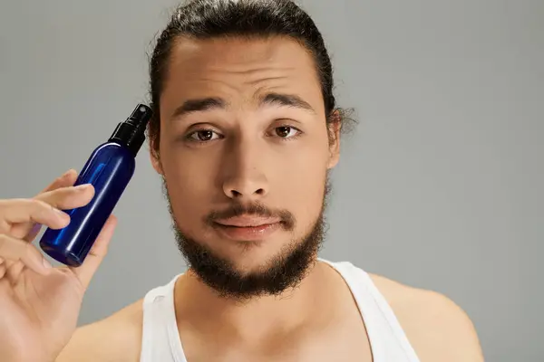 Confident young bearded man engages in grooming, showcasing a product while looking relaxed. — Stock Photo