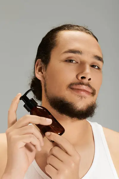 Joven muestra habilidades de aseo mientras usa un elegante producto de cuidado de la barba en interiores. - foto de stock
