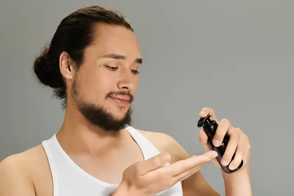 A young man with a beard enjoys applying a grooming product, showcasing his confidence. — Stock Photo