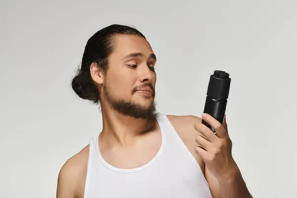 Focalizzato giovane uomo con barba ammira un prodotto di toelettatura sotto luminose luci da studio. — Stock Photo