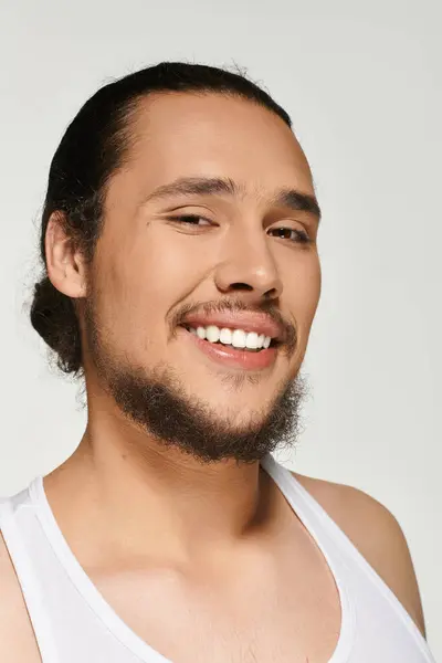 Charming young man with a well groomed beard showcases a joyful smile while posing indoors. — Stock Photo