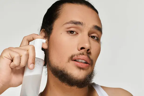 Young man with a beard expertly applies grooming product, showcasing his style and confidence. — Stock Photo