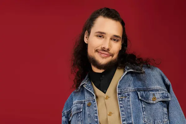 Young man exudes charm and style with his beard and long curls against a vibrant backdrop — Stock Photo