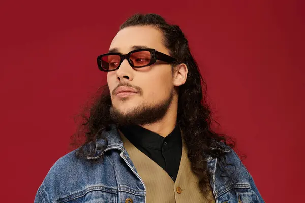 A stylish young man with a beard poses confidently in trendy glasses, exuding charisma and charm. — Stock Photo