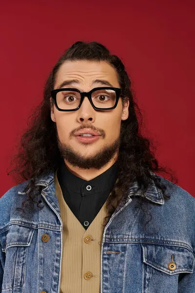 Beau jeune homme aux cheveux bouclés et à la barbe exprime sa surprise en posant pour la caméra. — Photo de stock