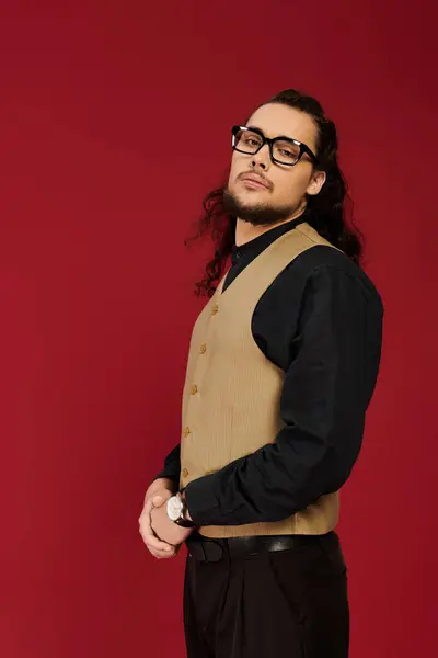 Striking young bearded man poses confidently, dressed in stylish attire with a bold backdrop. — Stock Photo