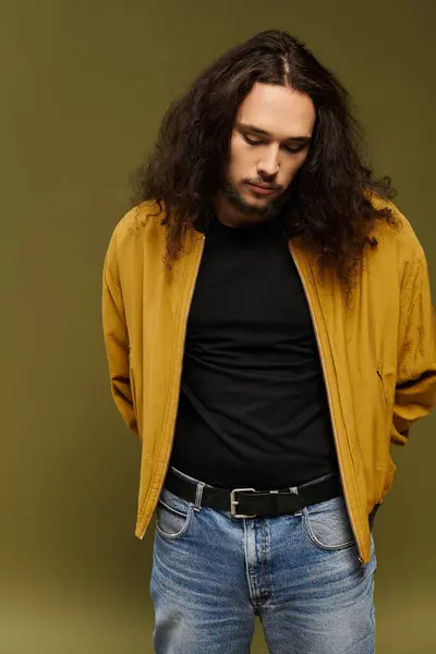 Handsome young bearded man dressed casually in a mustard jacket stands quietly in a studio. — стоковое фото