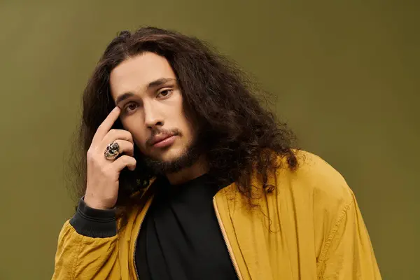 Young bearded man with curly hair poses thoughtfully, exuding style and confidence. — Stock Photo