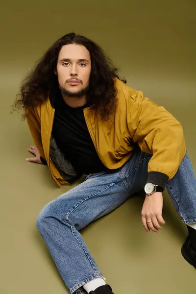 Young bearded man with long hair lounges in a vibrant setting, exuding style and confidence. — Stock Photo