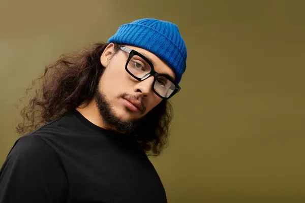 A stylish young man with a beard and glasses showcases his trendy look against a neutral backdrop. — Stock Photo
