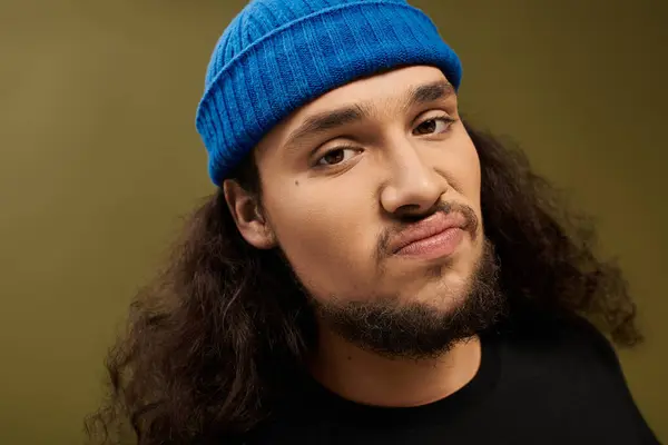 Young man with a well groomed beard and stylish blue beanie shows off his charm in a unique setting. — Stock Photo