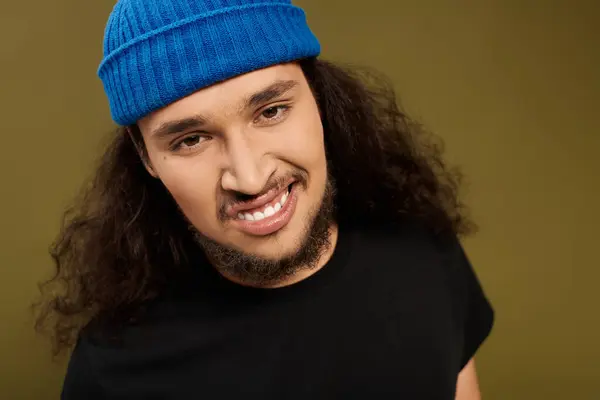 Young bearded man with curly hair enjoys a moment with a friendly smile in a cozy setting. — Stock Photo