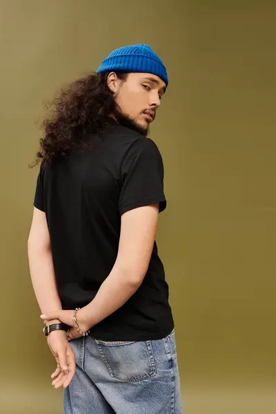 A striking young man with a well groomed beard confidently turns away from the camera. — Stock Photo