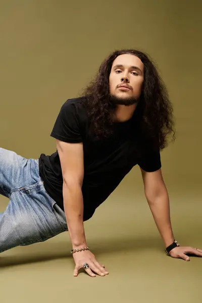Charismatic young man with a beard dynamically poses on one arm against a textured background. — Stock Photo