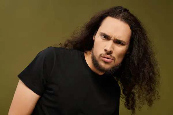 A young bearded man with curly hair gazes curiously towards the camera, showcasing his charm. — Stock Photo
