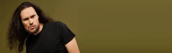 A bearded young man stands confidently, playfully posing against a soft backdrop. — Stock Photo