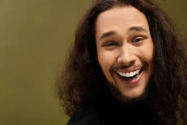 A handsome young bearded man smiles warmly, exuding charisma and confidence in a lively environment. — Stock Photo