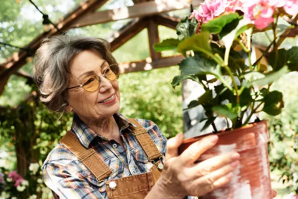 A joyful senior woman lovingly cares for her colorful flowers in a serene garden setting. — Stock Photo