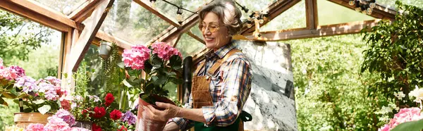 With a warm smile, an elegant senior woman tends to her colorful flowers in a lush garden. — стоковое фото
