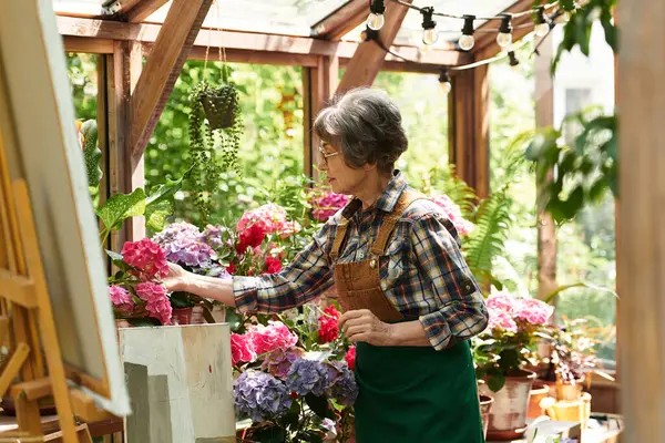 Beautiful senior woman carefully tending to colorful flowers in a charming garden area. — стоковое фото