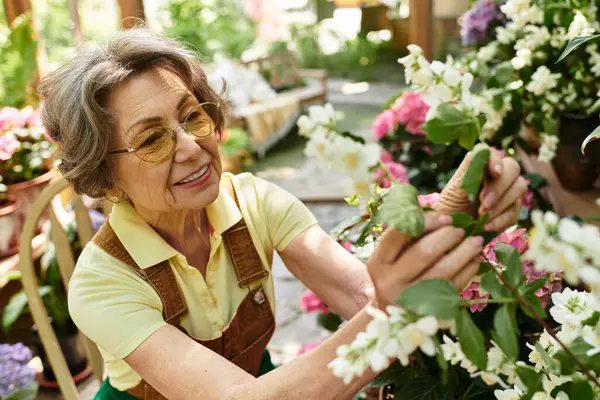 Joyful woman lovingly cares for vibrant blossoms in her serene garden during sunny afternoons. — стоковое фото