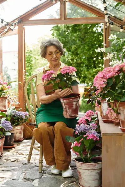 Senior woman enjoys nurturing blooming plants in a cheerful, sunlit garden arrangement. — стокове фото