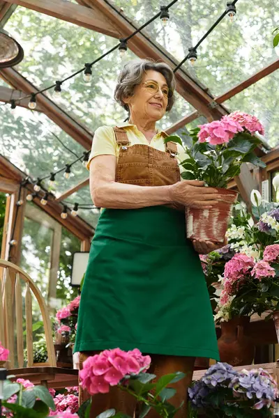 Senior woman carefully arranges colorful flowers while enjoying a sunny garden day. — Stock Photo